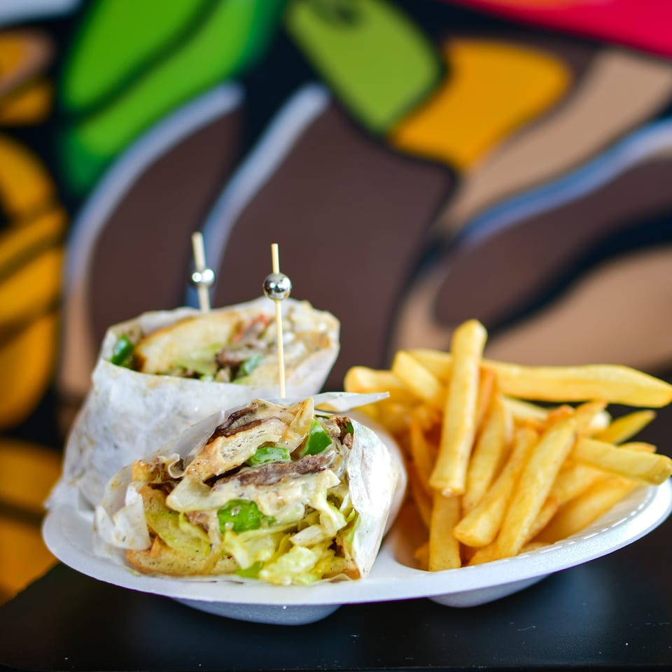 Two Canada Steak Burger wraps with steak, cheese, and vegetables, served with a side of fries.
